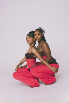 two women in red pants and black bra tops posing for the camera with their arms around each other