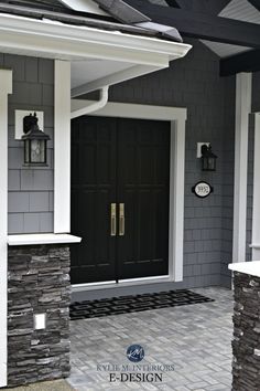 a black front door on a gray house with white trim and brick walkway leading up to it