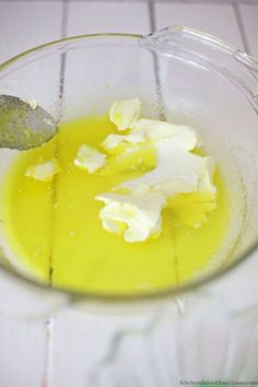 a bowl filled with yellow liquid and butter on top of a white tile countertop