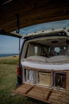 the back end of a van with its cargo compartment open and two large pillows on it