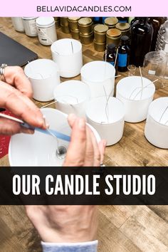 a person is holding a candle in front of some candles on a table with the words, our candle studio