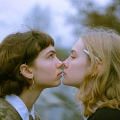 two women are kissing each other outside