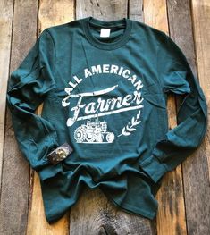 All American Farmer T-Shirt Show your support for our Farmers or if you are one wear it to show your pride. - Long Sleeve - Hunter Green - Graphic on Front - Unisex - Adulting Sizing - 52% Cotton/48% Polyester ***Cuff sold separately Agriculture Shirt, Grafic Tees, Farm Family, Farmer Shirt, Showing Livestock, Cute Country Outfits, Boutique Ideas, Cute Shirt Designs, Autumn T Shirts