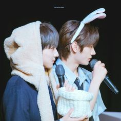 two young men with bunny ears on their heads, one holding a microphone and the other looking at something