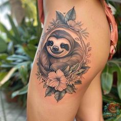 a sloth tattoo on the back of a woman's thigh with flowers and leaves around it