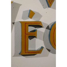 the letters e and f are painted yellow, blue, and grey on a white wall