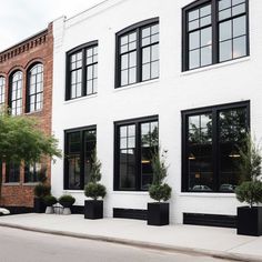 a white brick building with black windows and planters