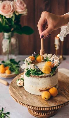 a person decorating a cake with oranges and flowers