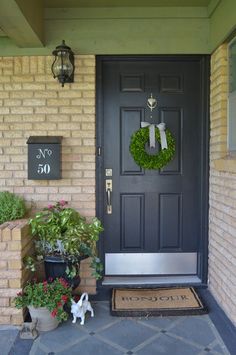 the front door is decorated with wreaths and potted plants