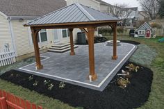 a backyard with a gazebo and landscaping in the background