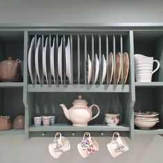 a shelf filled with dishes and cups on top of it's sides, next to a teapot