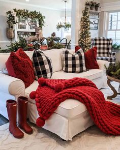 a living room filled with white furniture and red pillows on top of each other's blankets