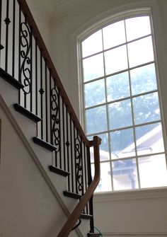 a stair case next to a window in a room with white walls and black railings