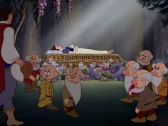 snow white and the seven dwarfs are in front of an old man laying on his stomach