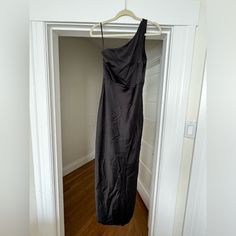 a black dress hanging on a hanger in an empty room with wood flooring