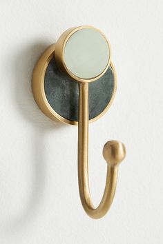 a gold coat hook with a mirror on it