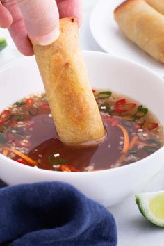 a person dipping sauce into a bowl of soup