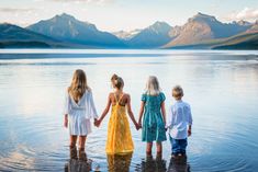 three girls and two boys are standing in the water with their arms around each other