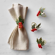 three napkins with holly and berries on them are sitting next to a cloth bag