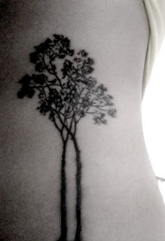 a woman's lower back with a tree tattoo on the side of her stomach