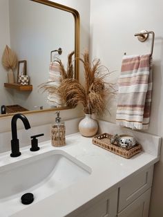 a bathroom with a sink, mirror and towels hanging on the rack in front of it