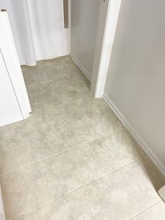 a white toilet sitting next to a bathroom sink under a shower curtain on top of a tiled floor