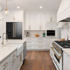 a kitchen with white cabinets and stainless steel appliances in the center, along with hardwood flooring