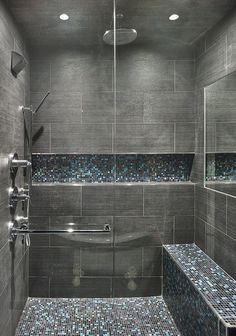 a walk in shower sitting next to a tiled wall and floor with blue tiles on the walls