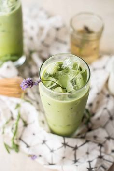 two glasses filled with green drinks on top of a table