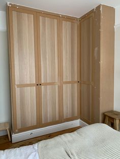 a bedroom with wooden closets and white sheets on the bed in front of it