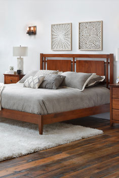 a bed sitting on top of a wooden floor next to a night stand with two lamps