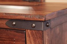 a close up of a wooden table with metal knobs on the top and bottom