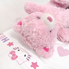 a pink teddy bear laying on top of a bed