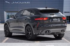 the rear end of a black suv parked in front of a jaguar dealership