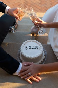 two people holding champagne glasses over a cake