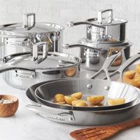 stainless steel pots and pans with wooden utensils on a marble countertop