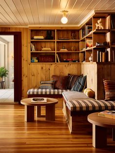 a living room filled with furniture and bookshelves next to a wooden floored wall