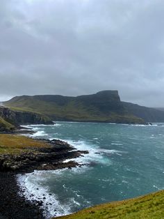 the ocean is blue and green with waves coming in from the shore on an overcast day