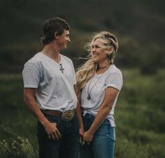 a man and woman are standing together in the grass with their hands behind their backs