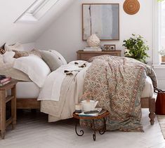 a bed sitting under a window in a bedroom next to a wooden table and chair