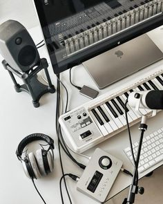 an electronic keyboard, headphones, and microphone on a white desk with a computer monitor