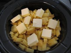 cubed potatoes in a slow cooker with butter on top, ready to be cooked