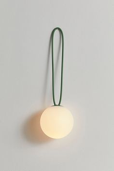 a white wall light with a green cord hanging from it's side on the wall