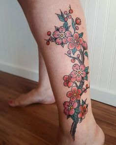 a woman's foot with a flower tattoo on the side of her leg,