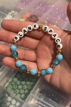 a hand holding a beaded bracelet with words on it and beads in the middle