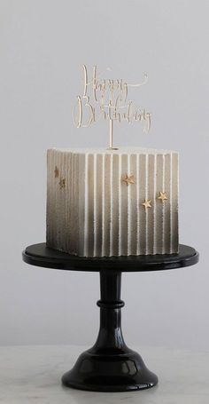 a birthday cake with white frosting and gold stars on top is sitting on a black plate