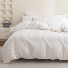 an unmade bed with white comforter and pillows on top of it in a bedroom