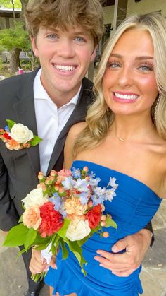 a man in a tuxedo poses with a woman in a blue dress