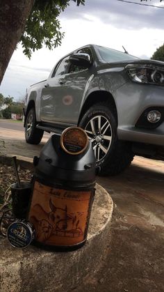 the truck is parked on the side of the road next to the tree and trash can