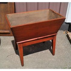 an old wooden planter sitting on the ground next to a wall with a door in it